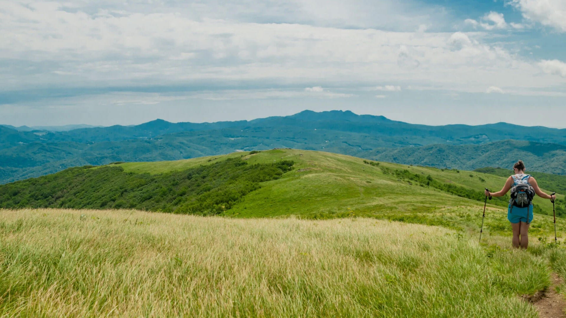 Hiker on mountain trail applying SolRX sunscreen at elevation on a sunny day