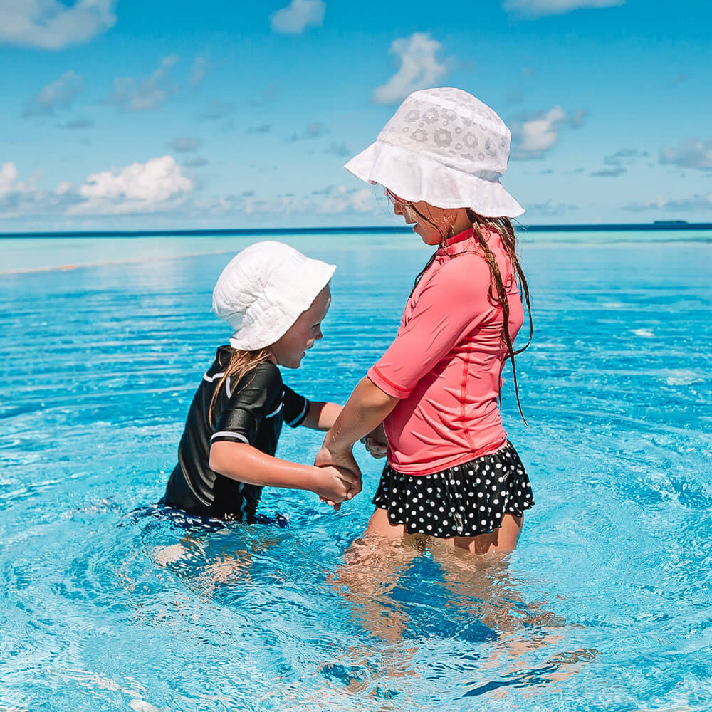 Two kids at pool edge smiling wet hair SolRX kids sunscreen hypoallergenic