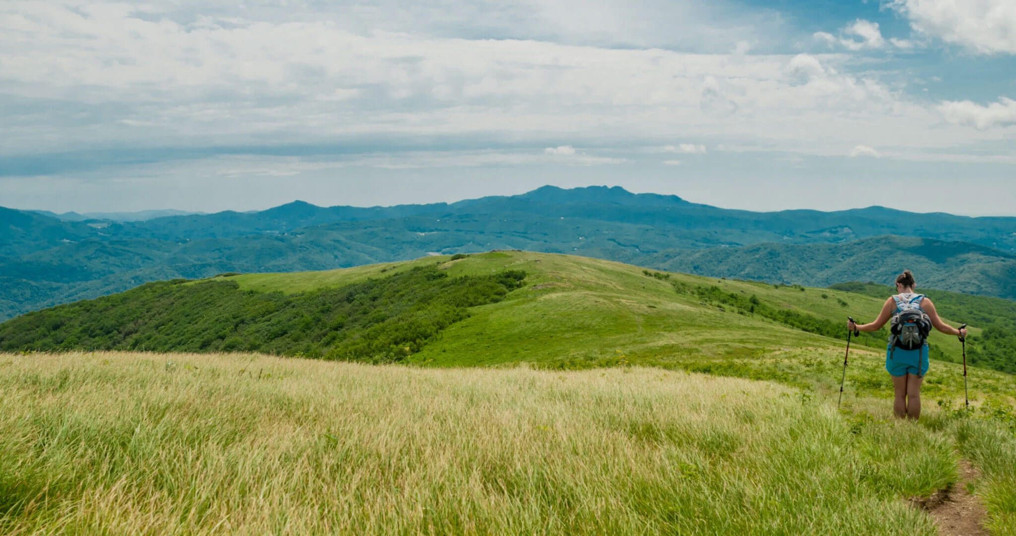 Hiker on mountain trail applying SolRX sunscreen at elevation on a sunny day