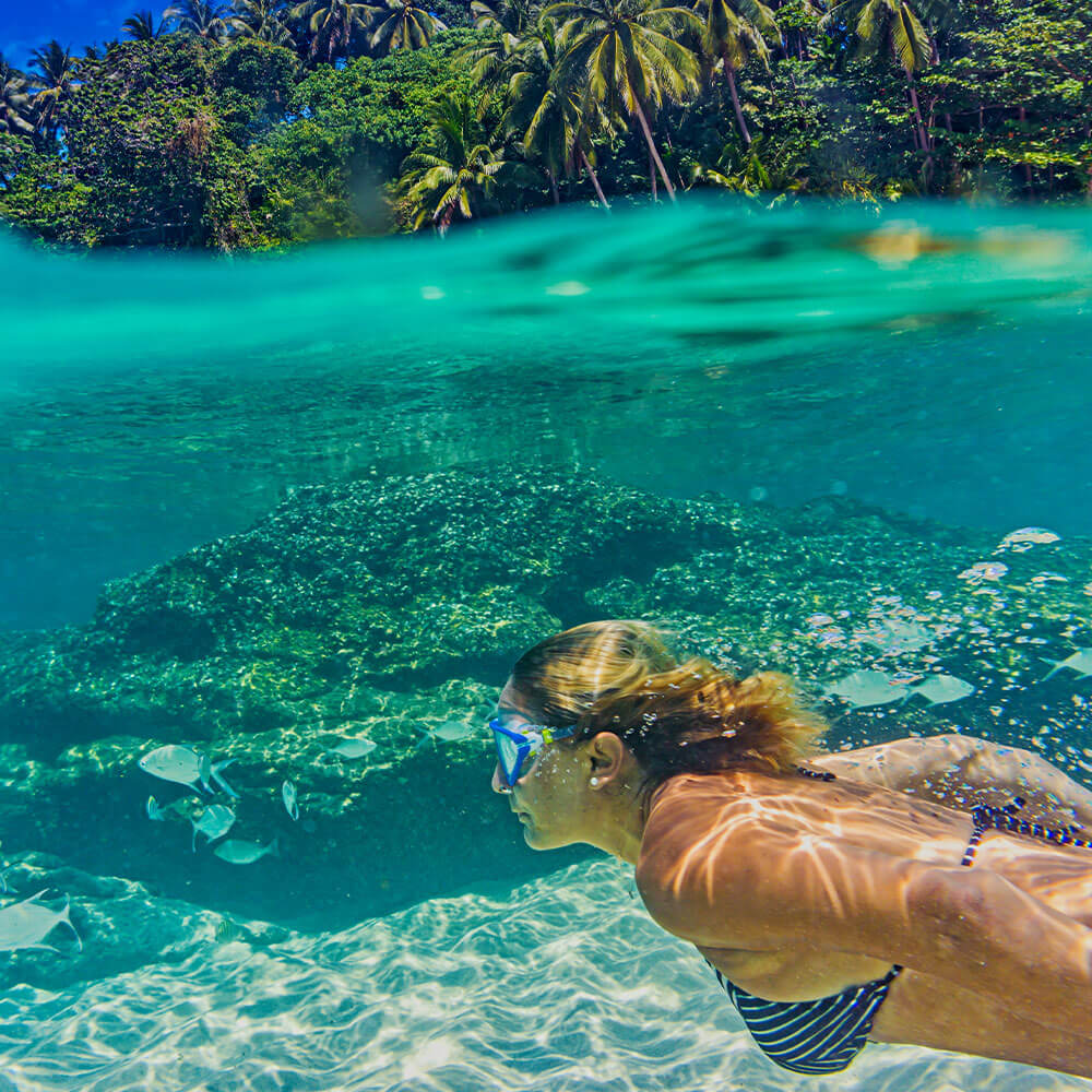 Snorkeler underwater coral reef clear turquoise water reef-safe sunscreen